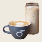 Hot latte in a gray Prasino cup next to an iced latte in a glass can